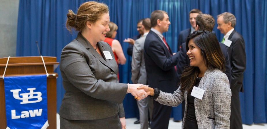 photo of dean aviva shaking hands with a law student at an event. 