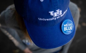 blue baseball cap that says UB University at Buffalo, and a pin that says "We Do Blue". 